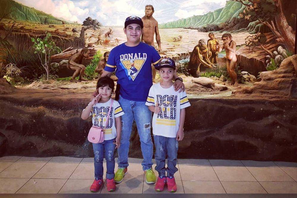 gambar ayah dan anak sedang berpose di depan lukisan manusia purba (instagram.com/harlinamua)