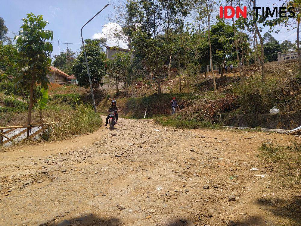 Pengendara Melintas Jalan di Desa Karyamukti, Kecamatan Cililin, KBB yang Rusak Parah. (Bangkit Rizki/IDN Times)