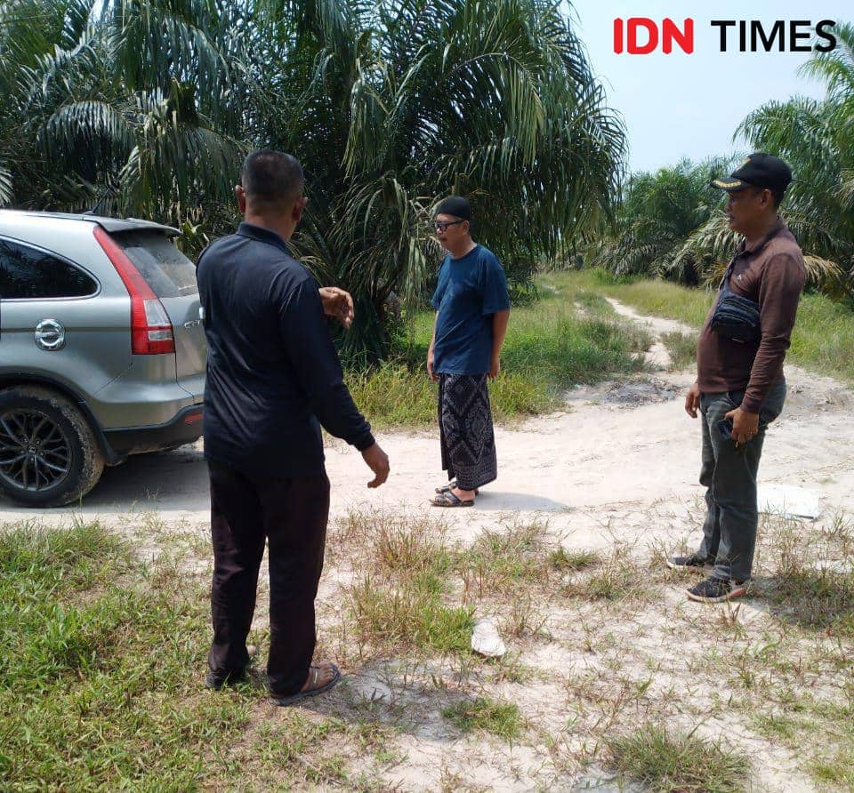 Tersangka Suparmin (tengah) saat dibawa keluar oleh AKP Selamet pergi ke kebun sawit (IDN Times/ Fanny Rizano)