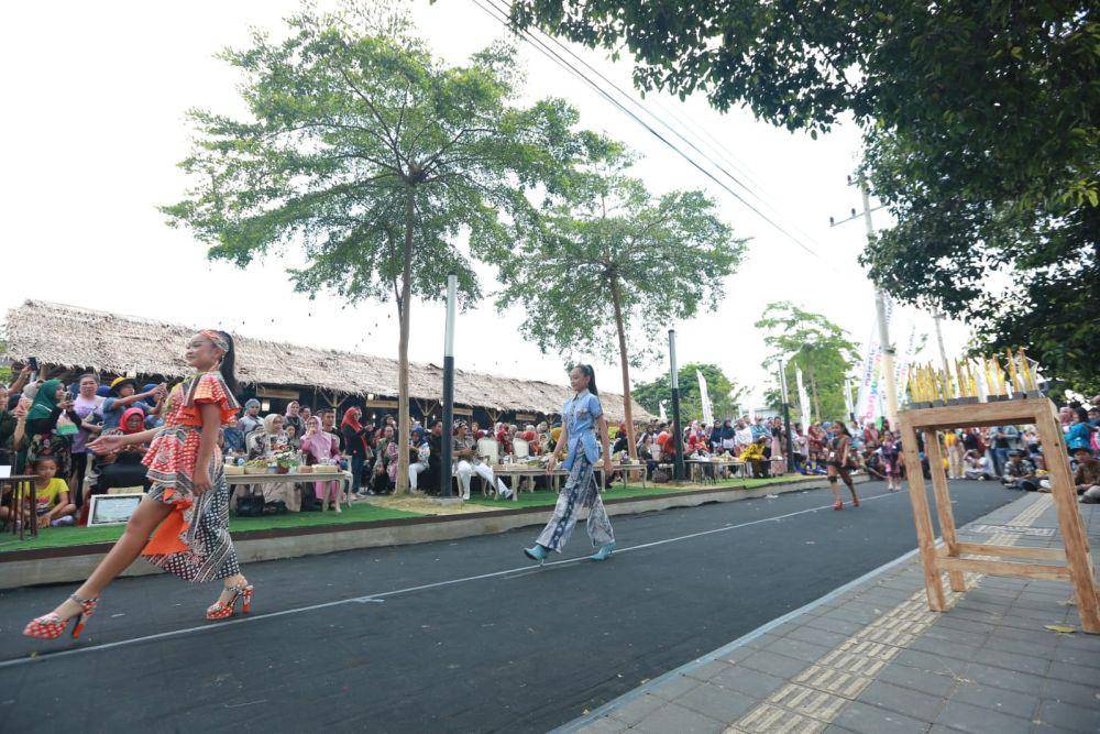 Puluhan peraga busana mengenakan batik berlenggak lenggok dengan menawan di sepanjang trotoar di depan area Banyuwangi Creative Hub yang berada di Terminal Pariwisata Terpadu, Banyuwangi. Para peraga tersebut tengah tampil dalam Fashion on Pedestrian yang digelar oleh Pemkab Banyuwangi, Jumat sore (20/10/2023). (Dok. Pemkab Banyuwangi)