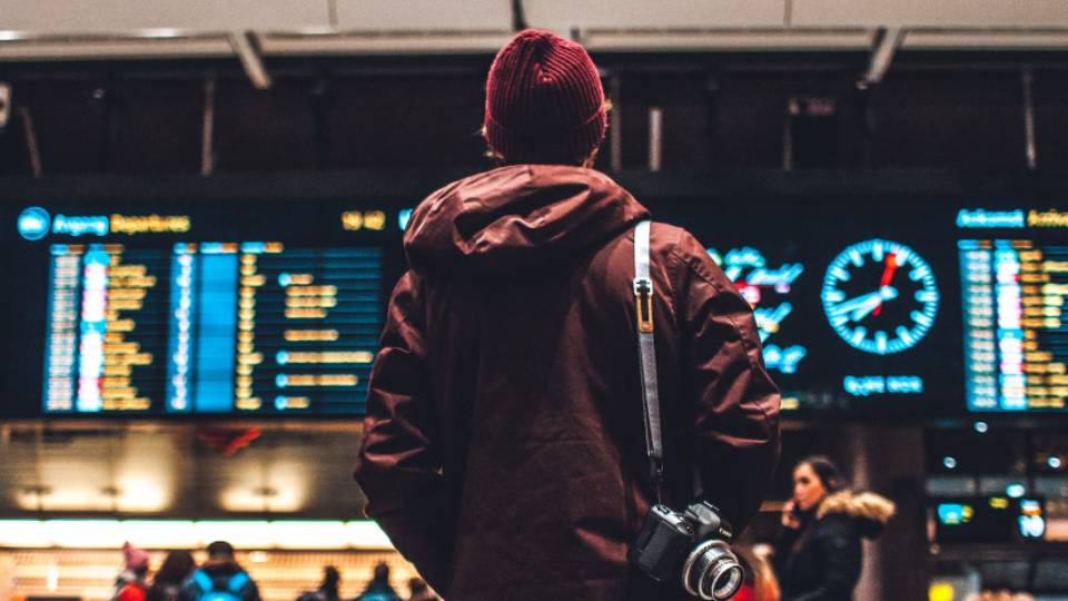 Ilustrasi pria melihat papan jadwal penerbangan bandara (unsplash.com/Erik Odiin)