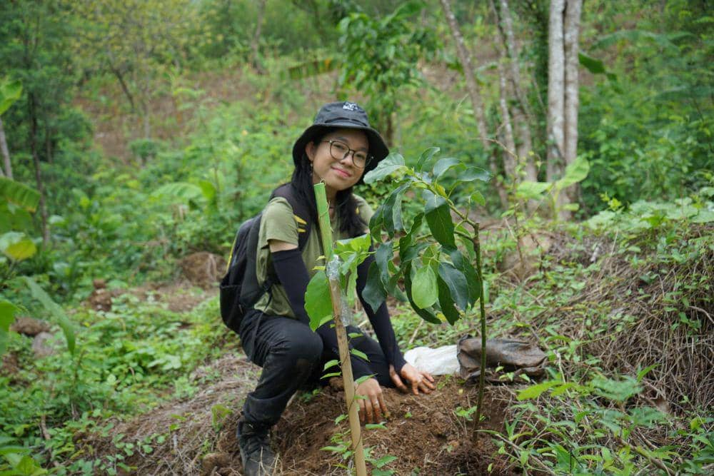 Seorang mahasiswi tersenyum ceria sambil memperlihatkan sebuah bibit pohon yang selesai ditanam di dekat kawasan perumahan Ayodhya Sekarang, Kecamatan Gunungpati. (IDN Times/Dok Humas Unnes)