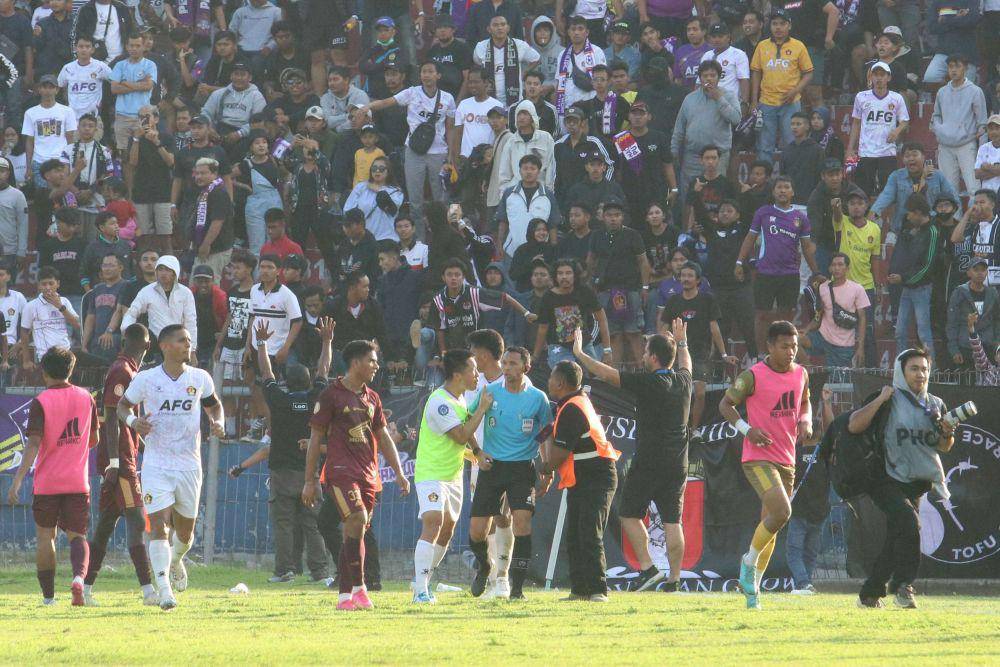 Petugas mengamankan wasit dari lemparan suporter saat pertandingan Persik Kediri melawan PSM Makassar pada kompetisi Liga 1 di Stadion Brawijaya, Kota Kediri, Jawa Timur, Senin (18/12/2023). ANTARA FOTO/Prasetia Fauzani/YU