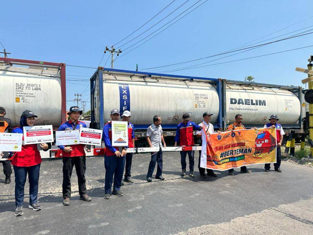 Petugas Balai Teknik Perkeretaapian Semarang membentangkan spanduk untuk menyosialisasikan keselamatan bagi masyarakat saat berkendara di jalur palang pintu kereta api. (IDN Times/Fariz Fardianto)
