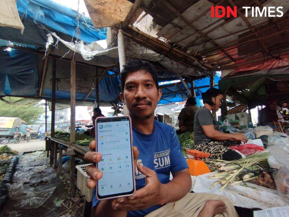 Seorang pedagang di Pasar Marelan menunjukkan aplikasi JMO BPJS Ketenagakerjaan (IDN Times/Doni Hermawan)