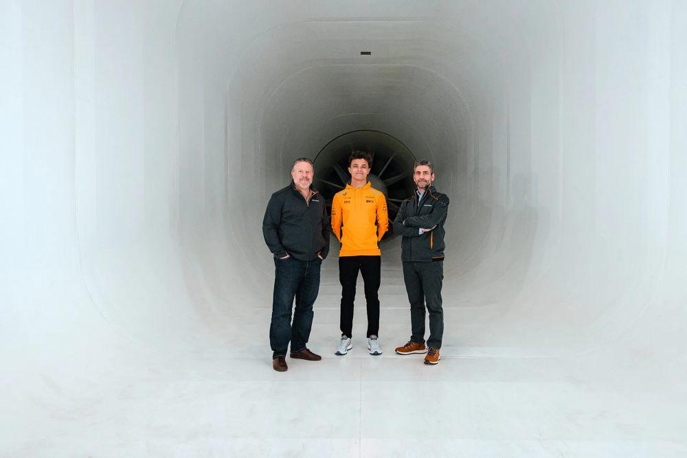 Zak Brown, Lando Norris, dan Andrea Stella berdiri di depan wind tunnel milik McLaren. (mclaren.com)