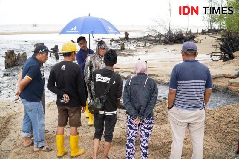 Pj Bupati PPU, Makmur Marbun pakai jas hujan berkomunikasi dengan warga korban banjir di sungai Parit PPU (IDN Times/Ervan)