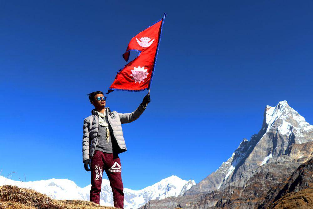 potret seseorang membawa bendera Nepal.(unsplash.com/ Arun Ghimire)