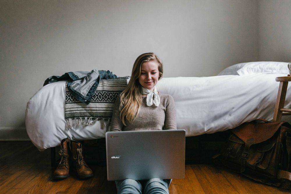 potret seorang wanita bermain laptop di kamar tidur (unsplash.com/Andrew Neel)