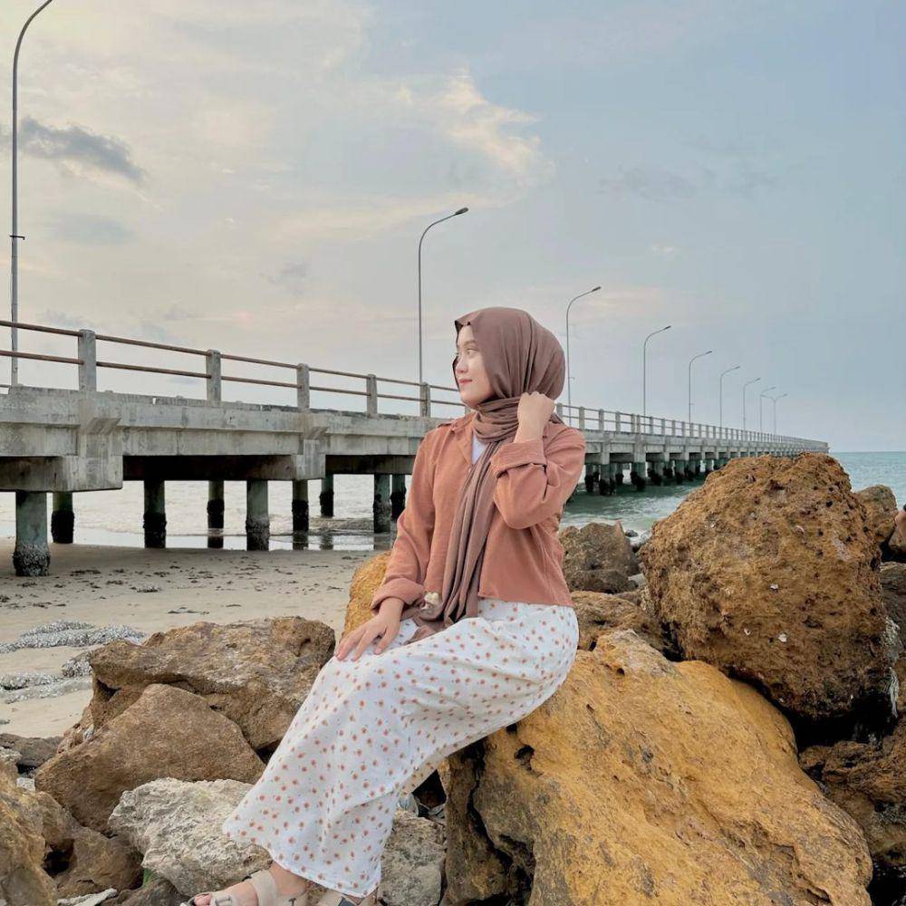 Pengunjung berfoto di atas bebatuan di Pantai Dermaga. Instagram/pantai_dermaga