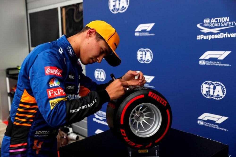 Lando Norris menandatangani ban Pirelli yang diberikan kepadanya sebagai apresiasi pencapaian pole position di sesi kualifikasi GP Rusia 2021. (twitter.com/Formula 1)