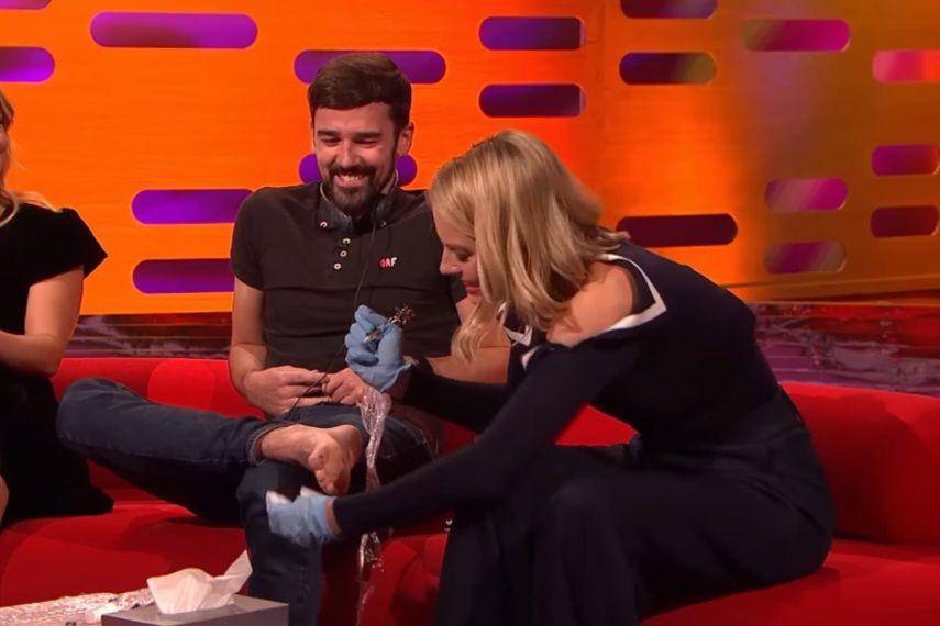 tangkapan layar Margot Robbie saat mentato jempol kaki crew TV dalam acara The Graham Norton Show (youtube.com/The Graham Norton Show)
