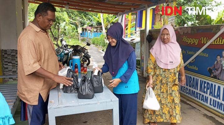 Suripto (kiri) saat menerima mendata dan memberikan beras bantuan dari para tetangga untuk warga lainnya, Jumat(2/1/2024).(IDN Times/Cokie Sutrisno)