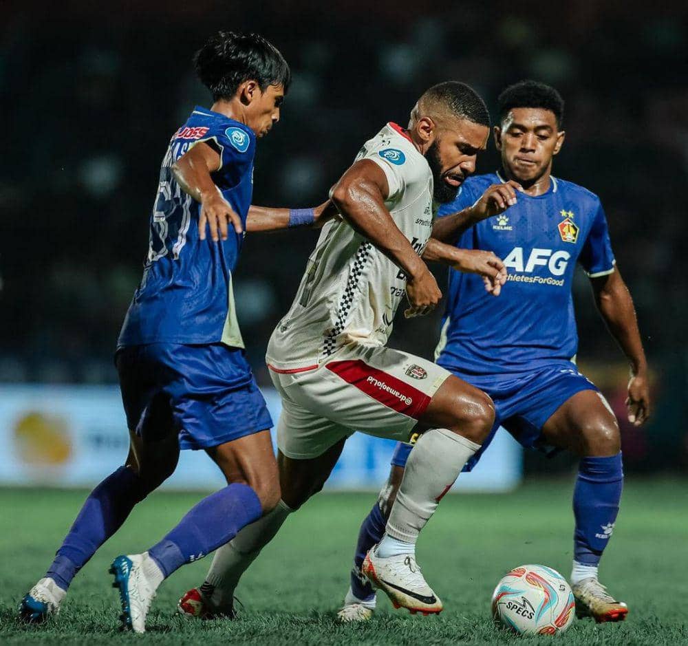 Pemain Bali United, Jefferson Assist (putih) sedang berebut bola dengan pemain Persik Kediri (biru). (Instagram.com/baliunitedfc)