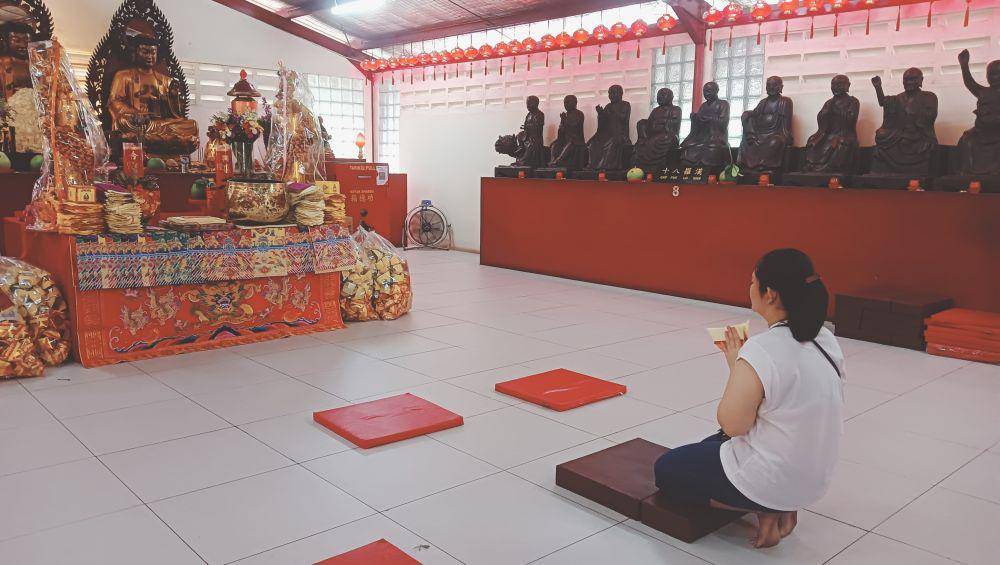 Seorang warga berlutut sembahyang menghadap patung Dewi Kwan Im. IDN Times/Sherlina Purnamasari