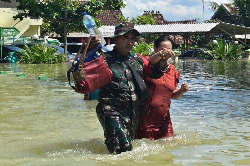 Seorang wanita dengan memakai daster cokelat saat dipapah oleh personel TNI di Kecamatan Karanganyar Demak. (IDN Times/Dok Pendam IV Diponegoro Semarang)