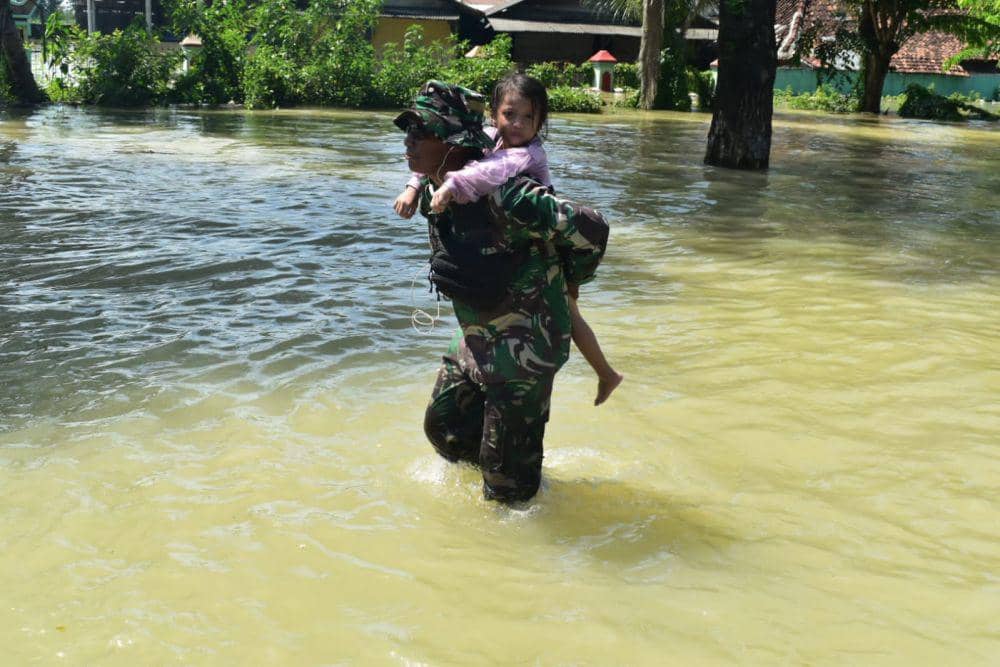 Seorang personel TNI saat menggendong seorang anak perempuan melewati banjir setinggi paha di Demak. (IDN Times/Dok Pendam Diponegoro Semarang)