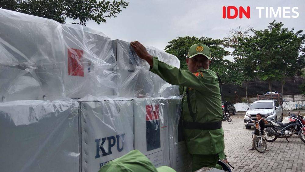 Seorang Linmas mengawal pengiriman logistik kotak suara dengan naik ke atas pikap. (IDN Times/Fariz Fardianto)