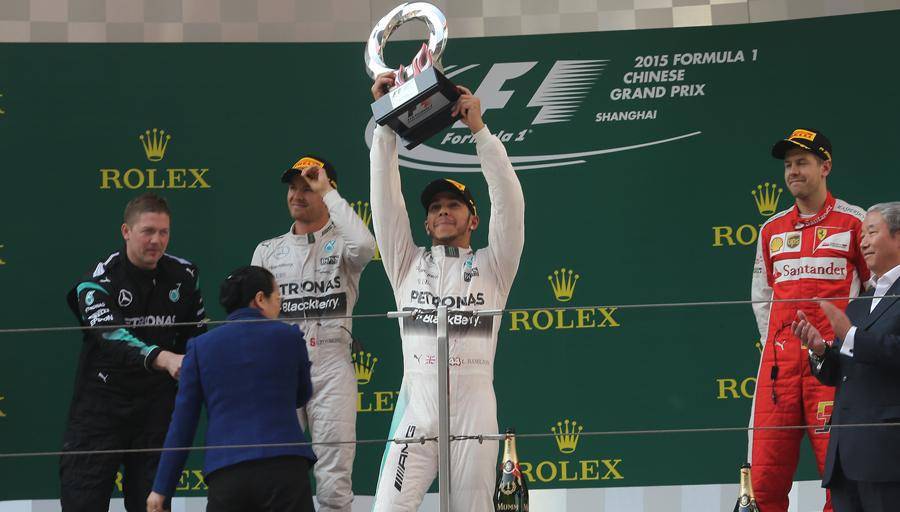 Lewis Hamilton (tengah) mengangkat trofi kemenangan GP China 2015 didampingi Nico Rosberg (kiri) di podium kedua dan Sebastian Vettel (kanan) di podium ketiga. (twitter.com/Formula 1)