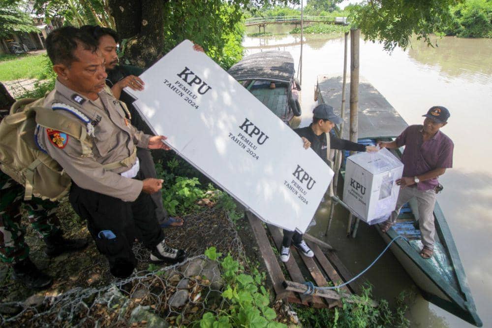 Petugas gabungan membawa kotak suara menggunakan perahu tradisional saat mendistribusikan logistik Pemilu ke TPS Dusun Kepetingan, Desa Sawohan, Kecamatan Buduran, Sidoarjo, Jawa Timur, Selasa (13/2/2024). Kelompok Penyelenggara Pemungutan Suara (KPPS) harus menyeberangi sungai untuk mendistribusikan logistik Pemilu 2024 ke TPS di kawasan terpencil. ANTARA FOTO/Umarul Faruq/foc.