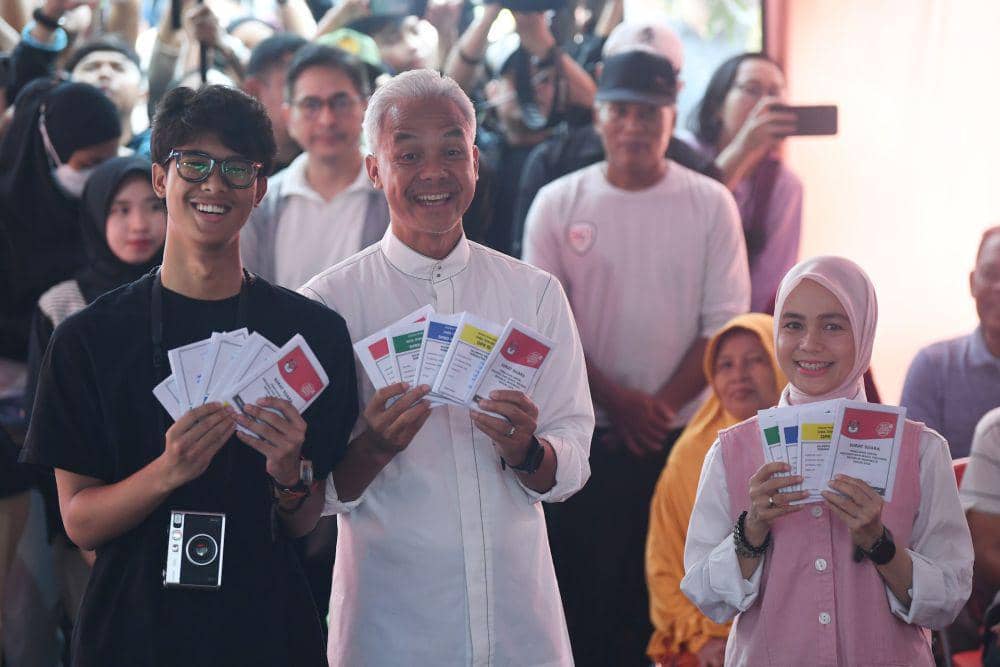 Calon presiden nomor urut 3 Ganjar Pranowo (tengah) bersama istri Siti Atikoh (kanan) dan anak Alam Ganjar (kiri) menunjukkan surat suara sebelum mencoblos di TPS 11 Lempongsari, Semarang, Jawa Tengah, Rabu (14/2/2024). (ANTARA FOTO/Akbar Nugroho Gumay)