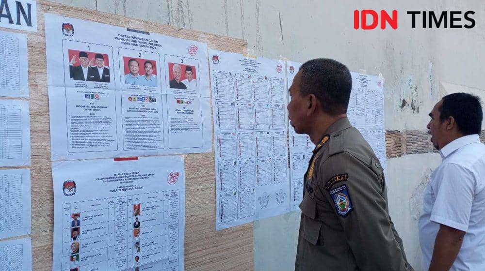 Seorang petugas Satpol PP NTB melihat contoh surat suara Pemilu 2024 di TPS 12 Lingkungan Karang Teruna Kota Mataram, Rabu (14/2/2024). (IDN Times/Muhammad Nasir)