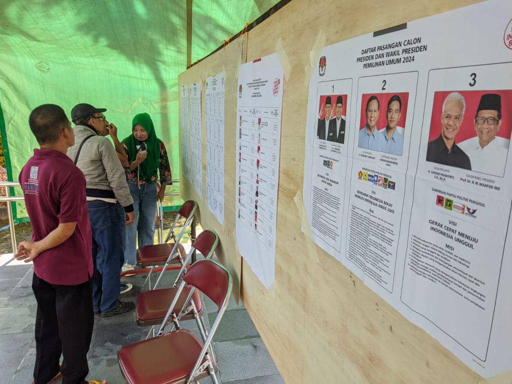 Sejumlah orang mengamati daftar calon legislatif Pemilu 2024 yang terpampang di TPS 005 Kelurahan Sinrijala, Kecamatan Panakkukang, Makassar, Rabu (14/2/2024). (IDN Times/Aan Pranata)