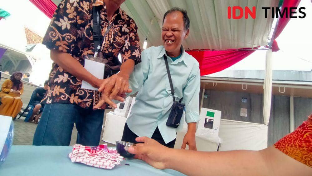 Yatimin (67) dan Suryana (50), pasangan suami istri (pasutri) penyandang disabilitas tunanetra di Kota Bandar Lampung salurkan suara ke TPS, Rabu (14/2/2024). (IDN Times/ Tama Yudha Wiguna).