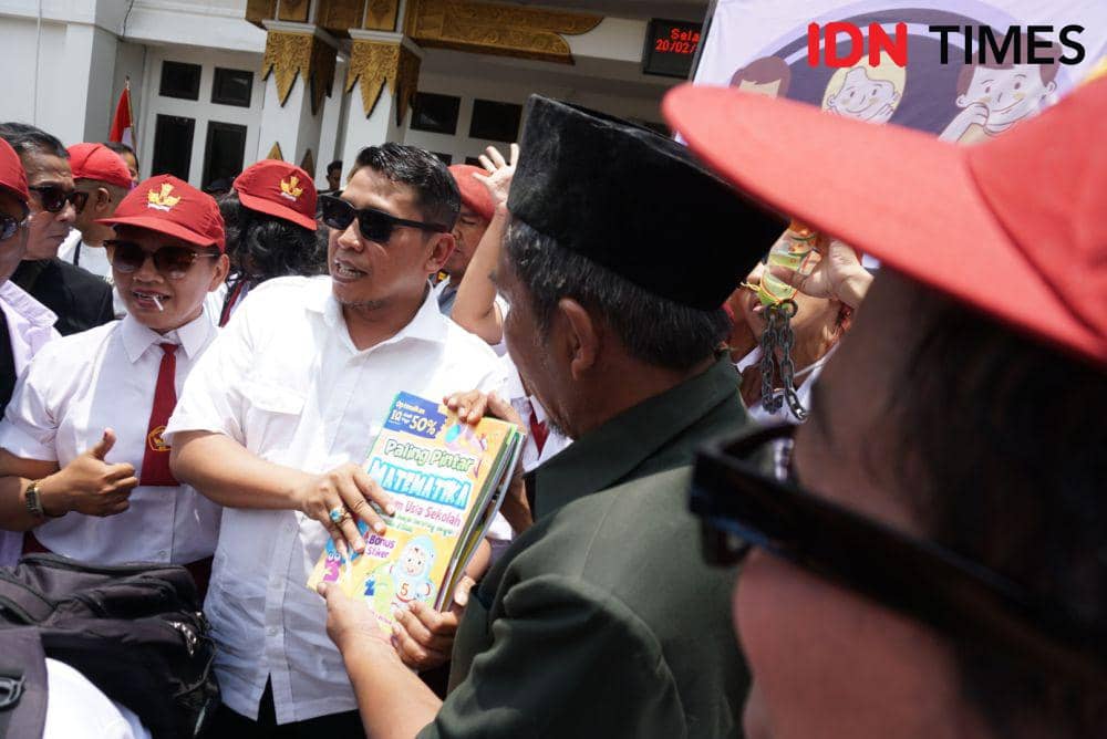 Ketua KPU DIY, Ahmad Shidqi (kiri) menerima buku matematika dari massa aksi, di Kantor KPU DIY, Selasa (20/2/2024). (IDN Times/Herlambang Jati Kusumo)