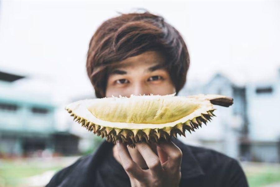 ilustrasi pria memegang durian sebagai makanan penyebab asam urat tinggi (freepik.com/peerafoto)