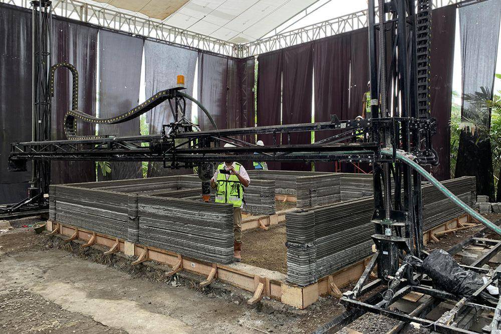 Seorang pekerja melakukan monitoring terhadap mesin 3D Printing yang sedang mencetak struktur dinding pada pembangunan rumah tapak di Sleman. (Dok. Istimewa)