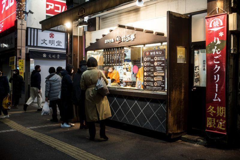 gambar orang berdiri di kios street food Jepang