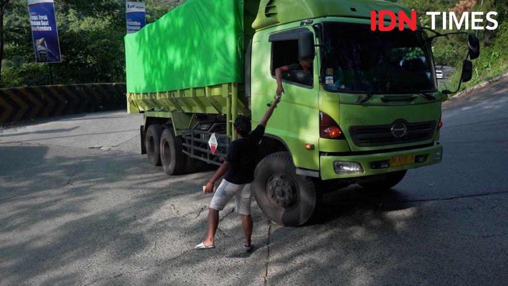 Potret Jaya menerima uang dari pengemudi truk yang melintas di Sitinjau Lauik (IDN Times/Athif Aiman)