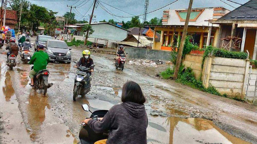 potret melintasi jalan yang rusak (voi.id)
