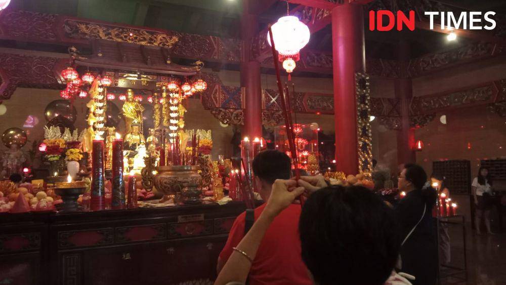 Seorang umat Tri Dharma mengangkat hio saat berdoa di depan altar utama dewa-dewi di Klenteng Low Lie Bio Semarang. (IDN Times/Fariz Fardianto)
