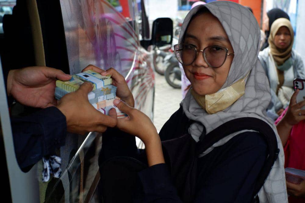 Warga memamerkan uang baru yang baru ditukar. IDN Times/ Bramanta Pamungkas