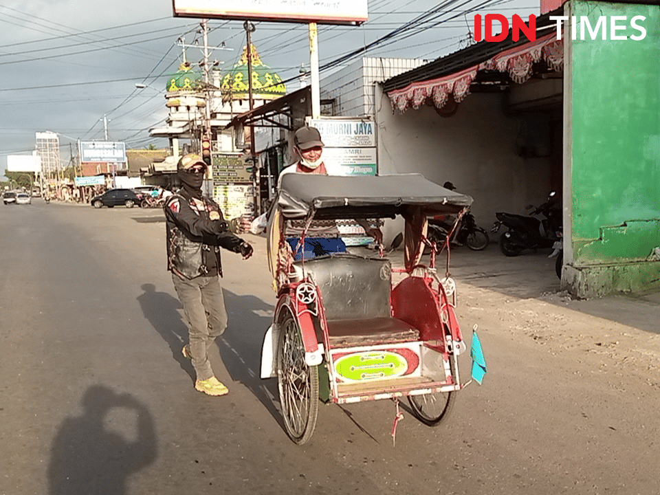 Salah satu anggota AKBI saat akan bagikan takjil ke abang becak yang melintas di perempatan Buntu, Minggu (31/3/2024).(IDN Times/Cokie Sutrisno)