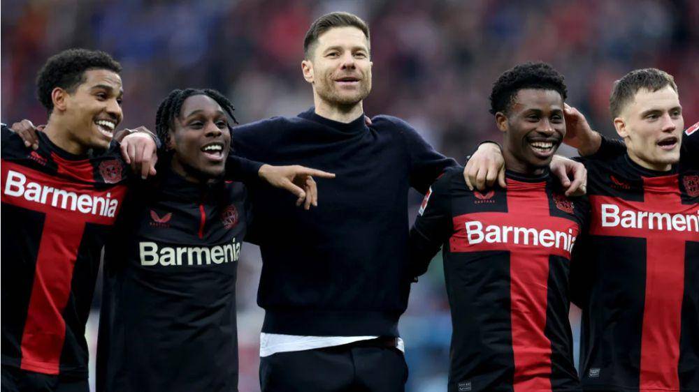 Xabi Alonso (tengah) sedang mengikuti euforia bersama para pemain Bayer Leverkusen. (bundesliga.com)