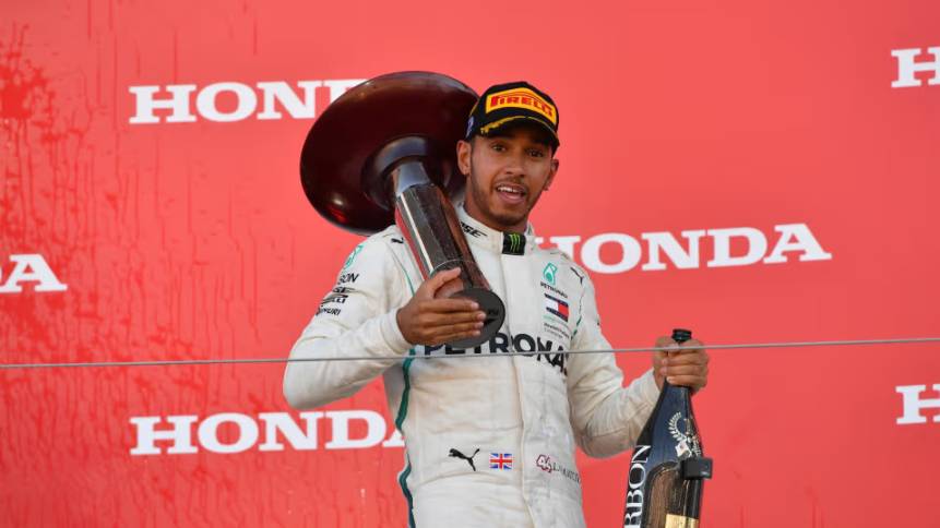 Lewis Hamilton memegang botol champagne dan trofi kemenangan GP Jepang 2018. (formula1.com)