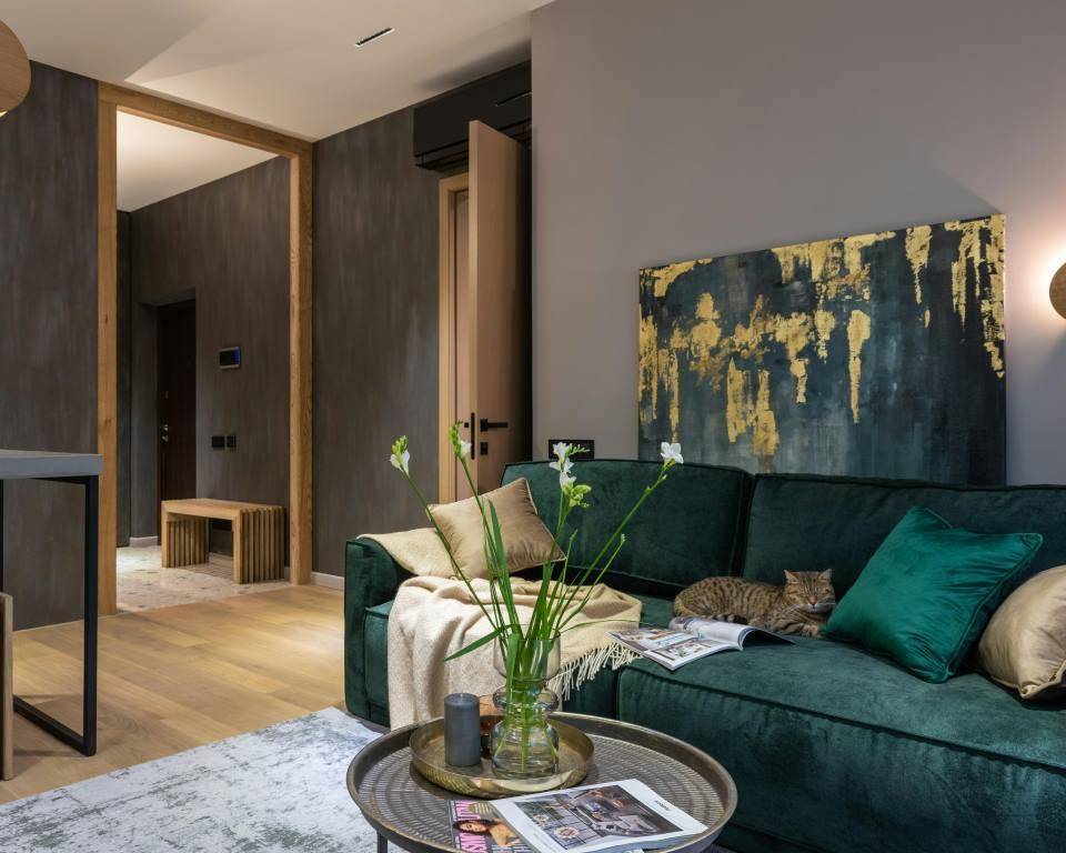ilustrasi sofa hijau gelap di ruangan abu-abu (pexels.com/Max Vakhtbovycn)
