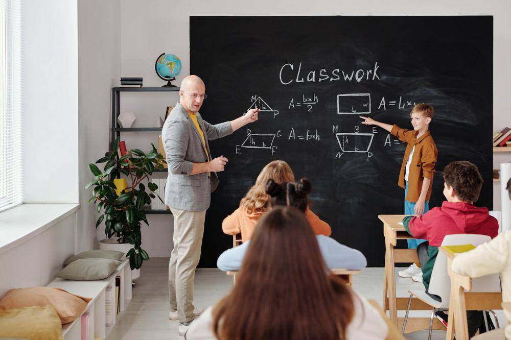 ilustrasi guru menjelaskan materi di depan kelas (pexels.com/Max Fischer)