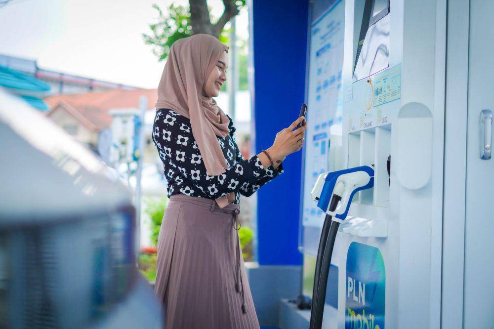 Ilustrasi pengguna mobil listrik yang sedang mengisi daya di SPKLU. (dok. PLN)
