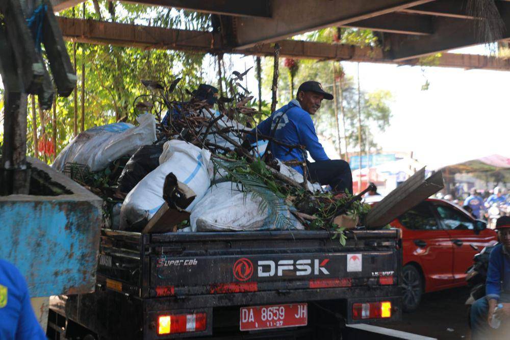 Sampah yang dipungut di sungai diangkut ke pikap.