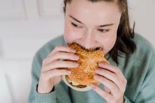 ilustrasi perempuan sarapan burger (pexels.com/@tim-samuel/)