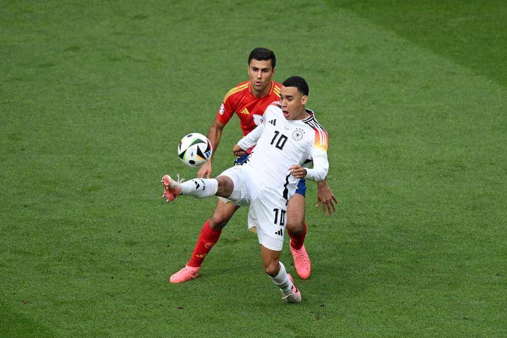Jamal Musiala (putih) mempertahankan bola dari Rodri di Euro 2024. (uefa.com)