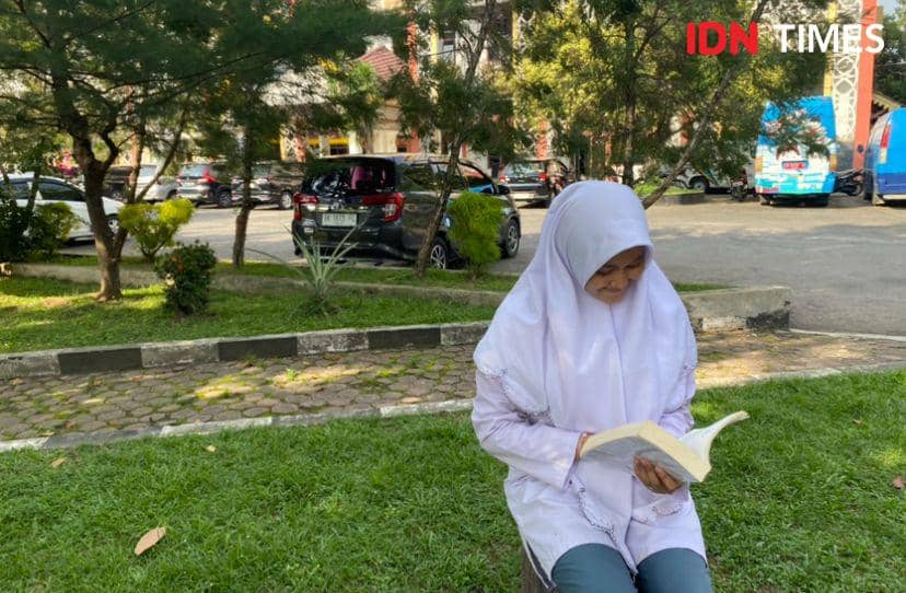 Salah satu pengunjung yang membaca buku didepan Perpustakaan Sumut (IDN Times/Indah Permata Sari)