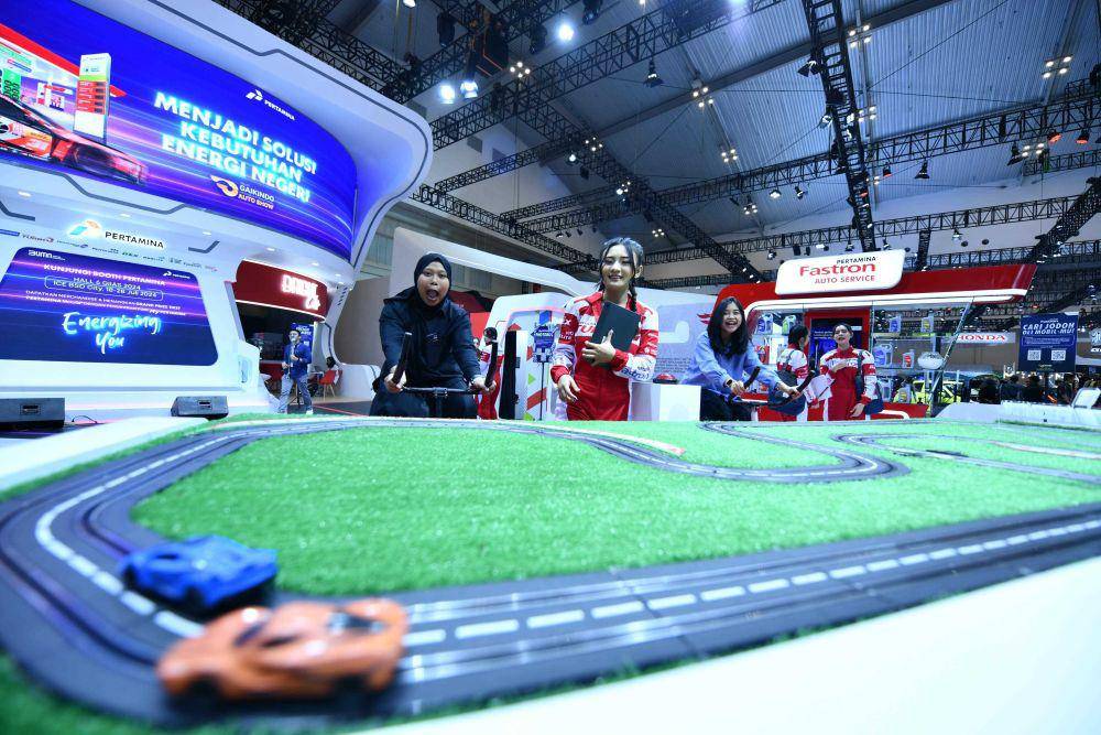 Salah satu pengunjung sangat antusias menikmati balapan miniatur mainan dengan menggowes sepeda kinestetik di Booth Pertamina GIIAS 2024 di ICE BSD, Jumat (26/7). (dok. Pertamina)