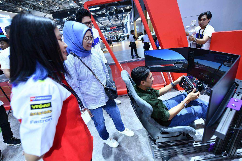 Direktur Keuangan PT Pertamina (Persero) Emma Sri Martini mencoba Games Mandalika Max Race di Booth Pertamina dalam acara GAIKINDO Indonesia International Auto Show (GIIAS) di ICE BSD, Jumat (26/7). (dok. Pertamina)