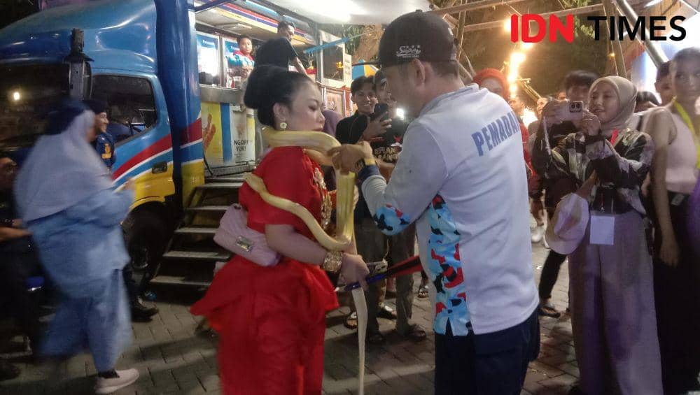 Seorang pengunjung dililitkan ular ke lehernya oleh petugas Damkar di F8, Jumat (26/7/2024). (IDN Times/Asrhawi Muin)