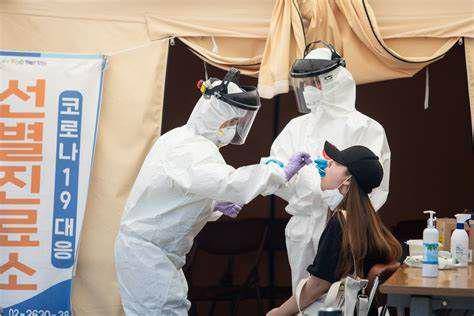 petugas medis dengan alat pelindung mengumpulkan sampel dari seseorang di stasiun pengujian virus corona di Seoul, Korea Selatan, pada 11 Juni 2020 (Getty Images/Chris Jung)